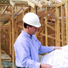 Man in a hard hat reading plans at a construction site.